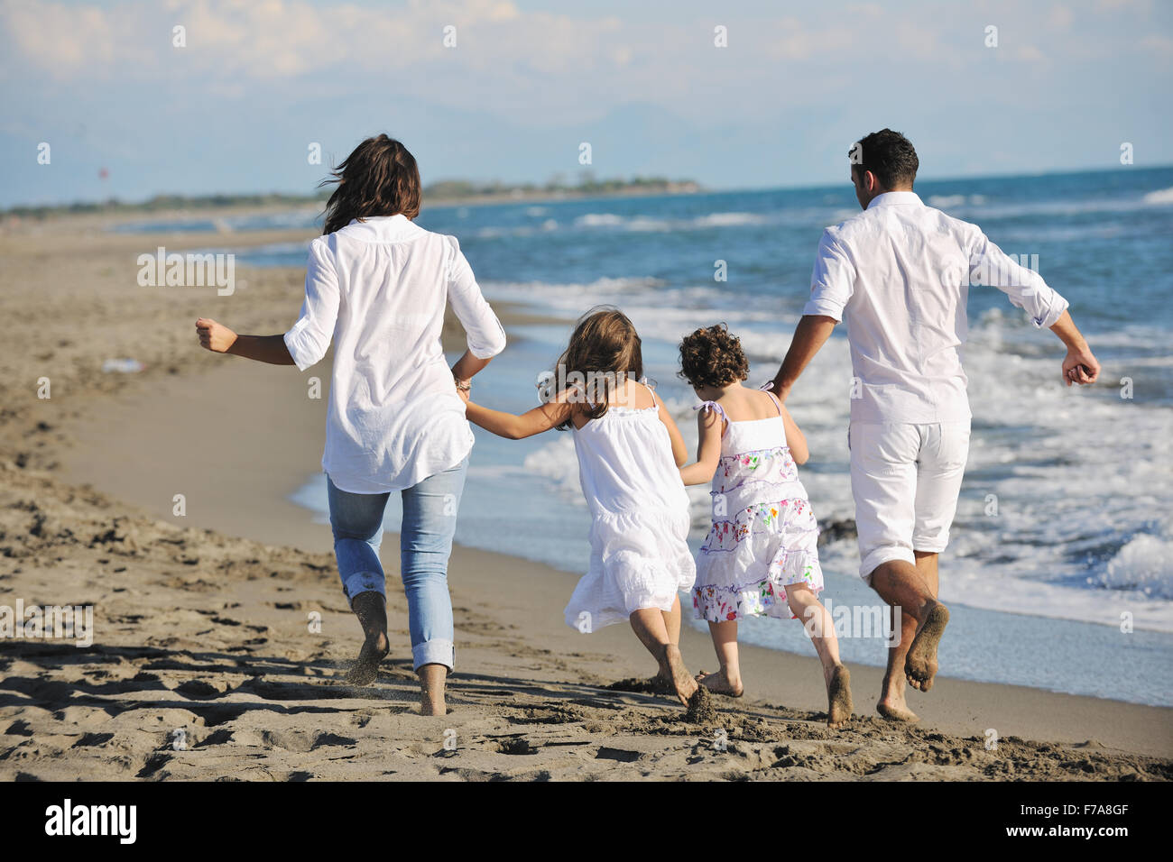 glückliche junge Familie in weißer Kleidung viel Spaß im Urlaub am schönen Strand