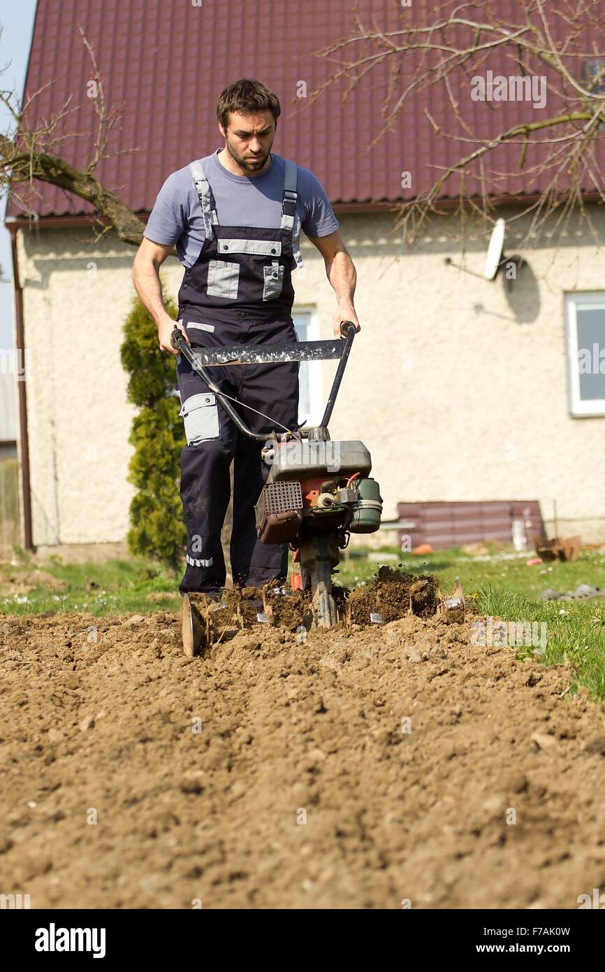 Mann ein Feld mit Hand motor Pflug Pflügen. Stockfoto