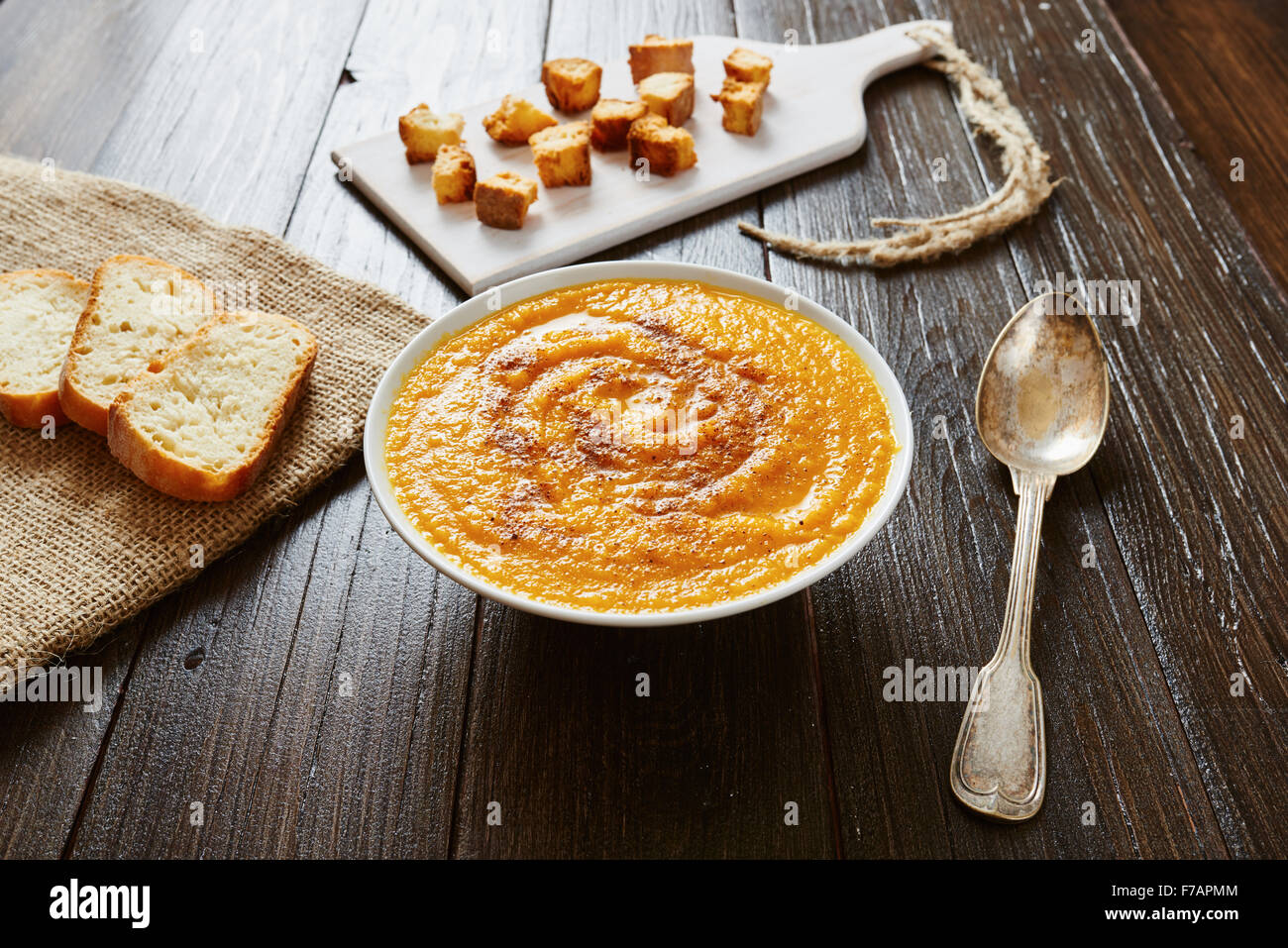 Kürbissuppe in weiße Schüssel mit Brot Croutons auf Holztisch Stockfoto