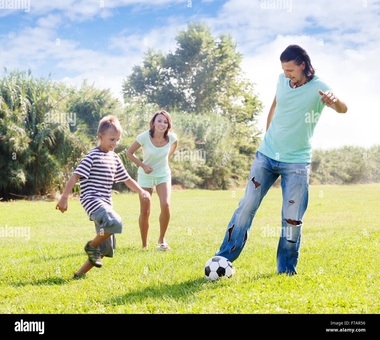 Glückliche Eltern mit Kind im Sommer mit Fußball spielen Stockfoto