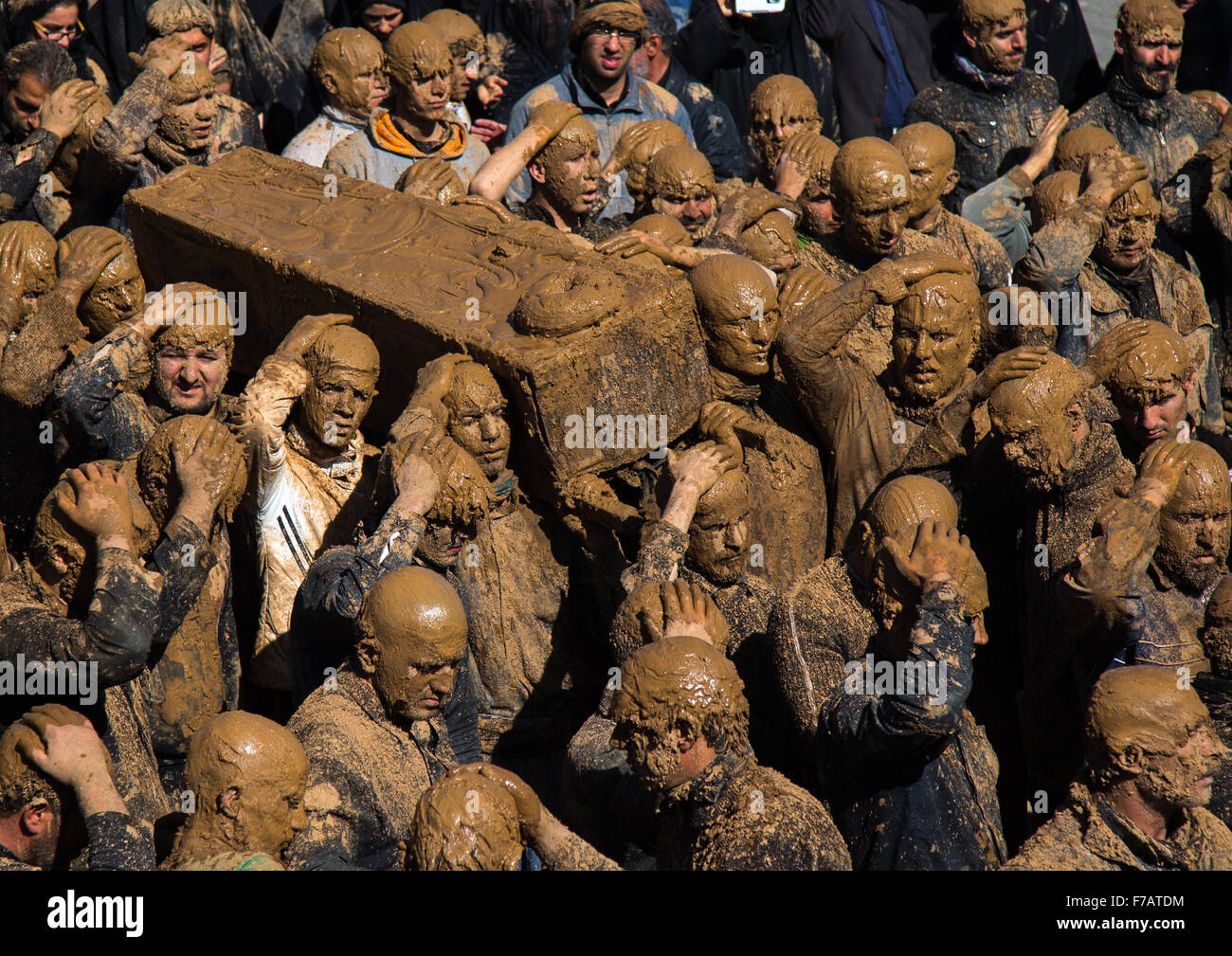 Iranische Schiiten muslimische Männer bedeckt im Schlamm mit einem Sarg während Ashura, der Tag des Todes von Imam Hussein, Provinz Kurdistan, Bidjar, Iran Stockfoto