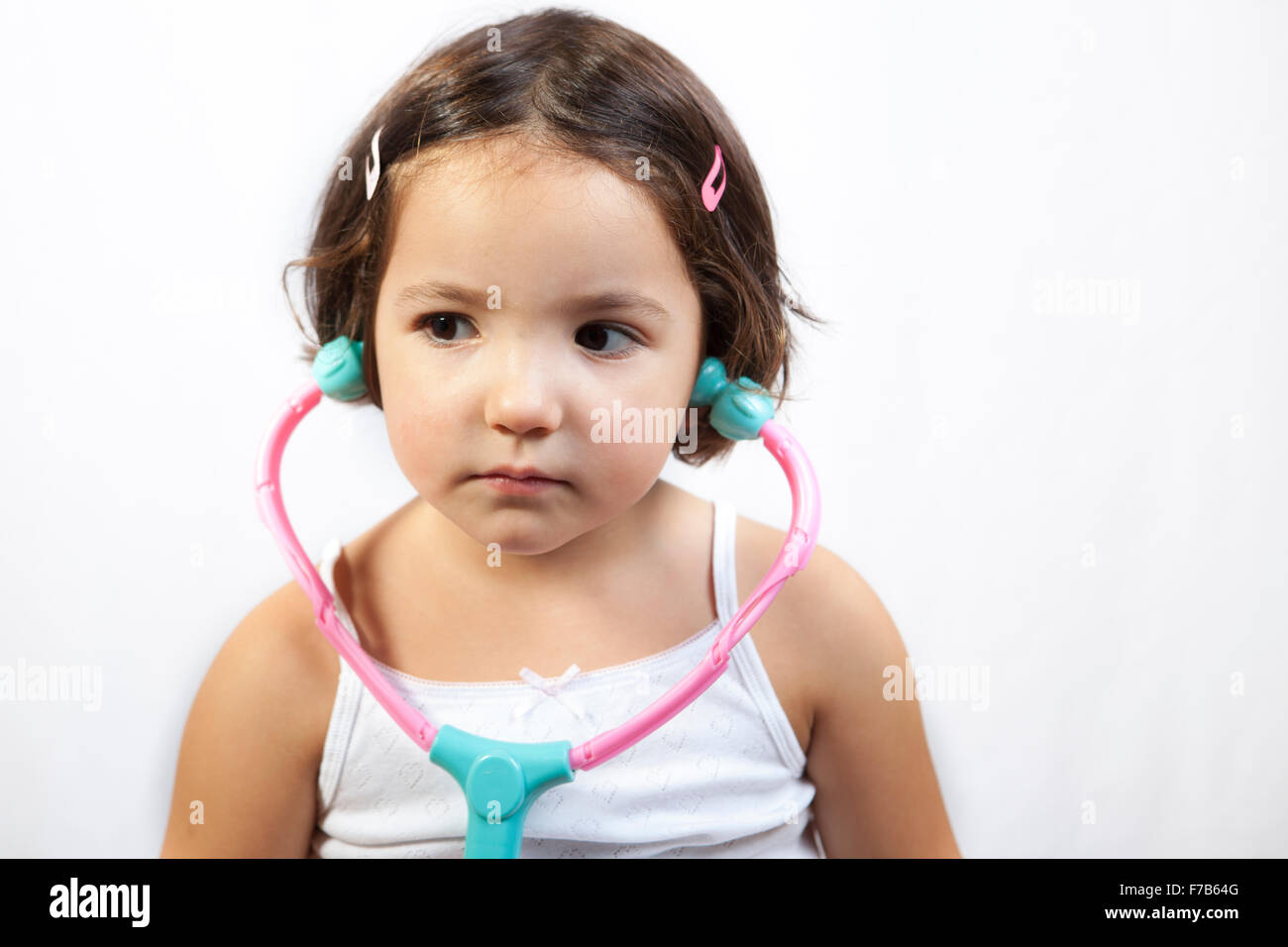 Niedliche kleine Mädchen spielen Arzt mit Stethoskop Spielzeug. Isoliert auf weißem Hintergrund Stockfoto