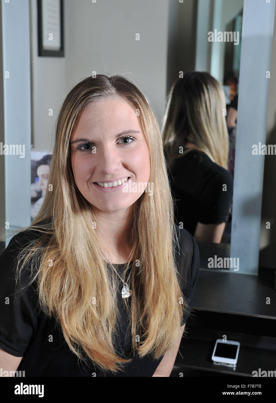 Junge Frau mit langen blonden Haaren, die es für wohltätige Zwecke in einem Friseursalon in Großbritannien abschneiden wird Stockfoto