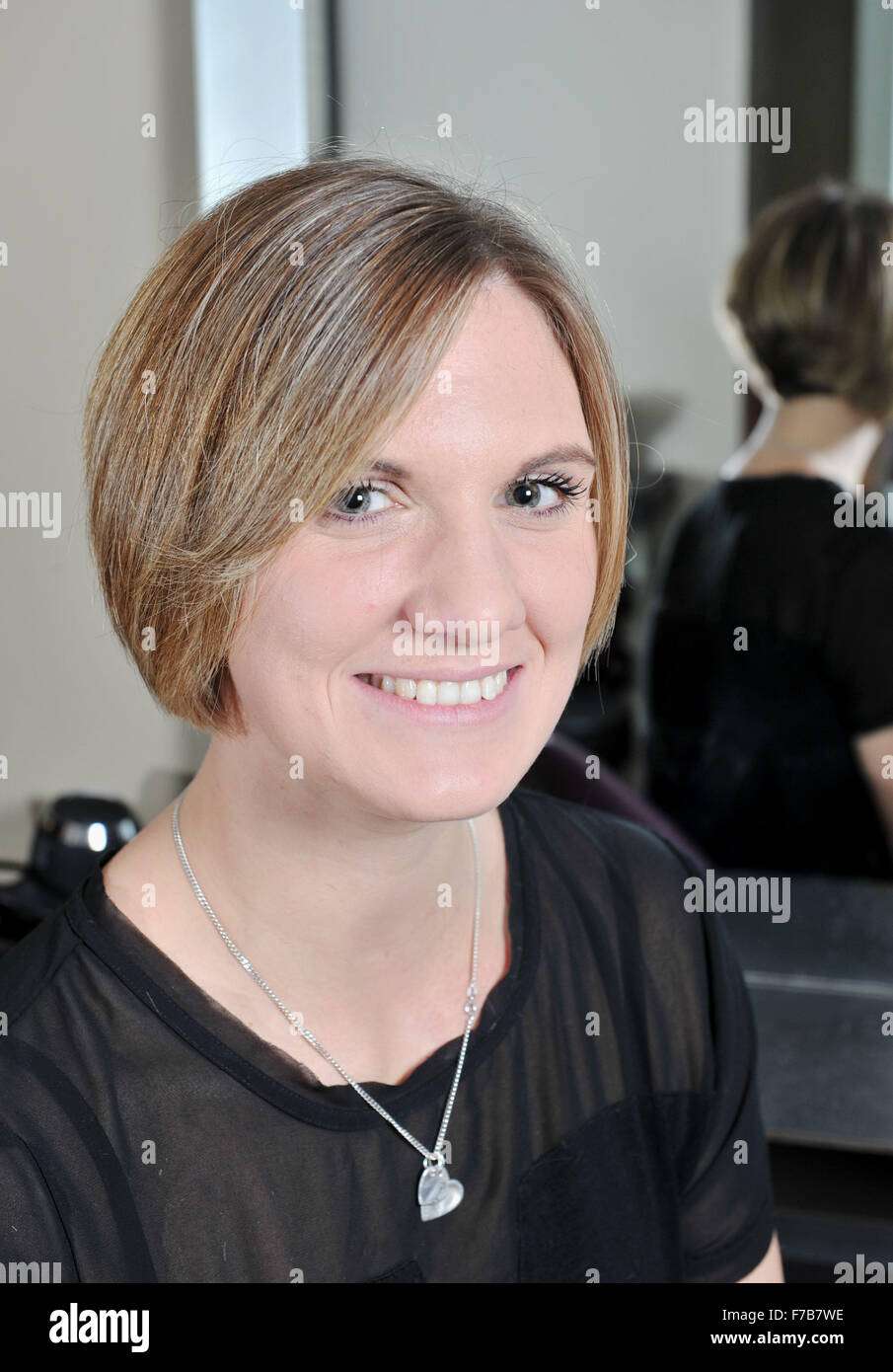 Porträt einer jungen Frau in ihren 20s Jahren mit kurzen Haaren in einem Friseursalon, nachdem es für wohltätige Zwecke geschnitten wurde Stockfoto