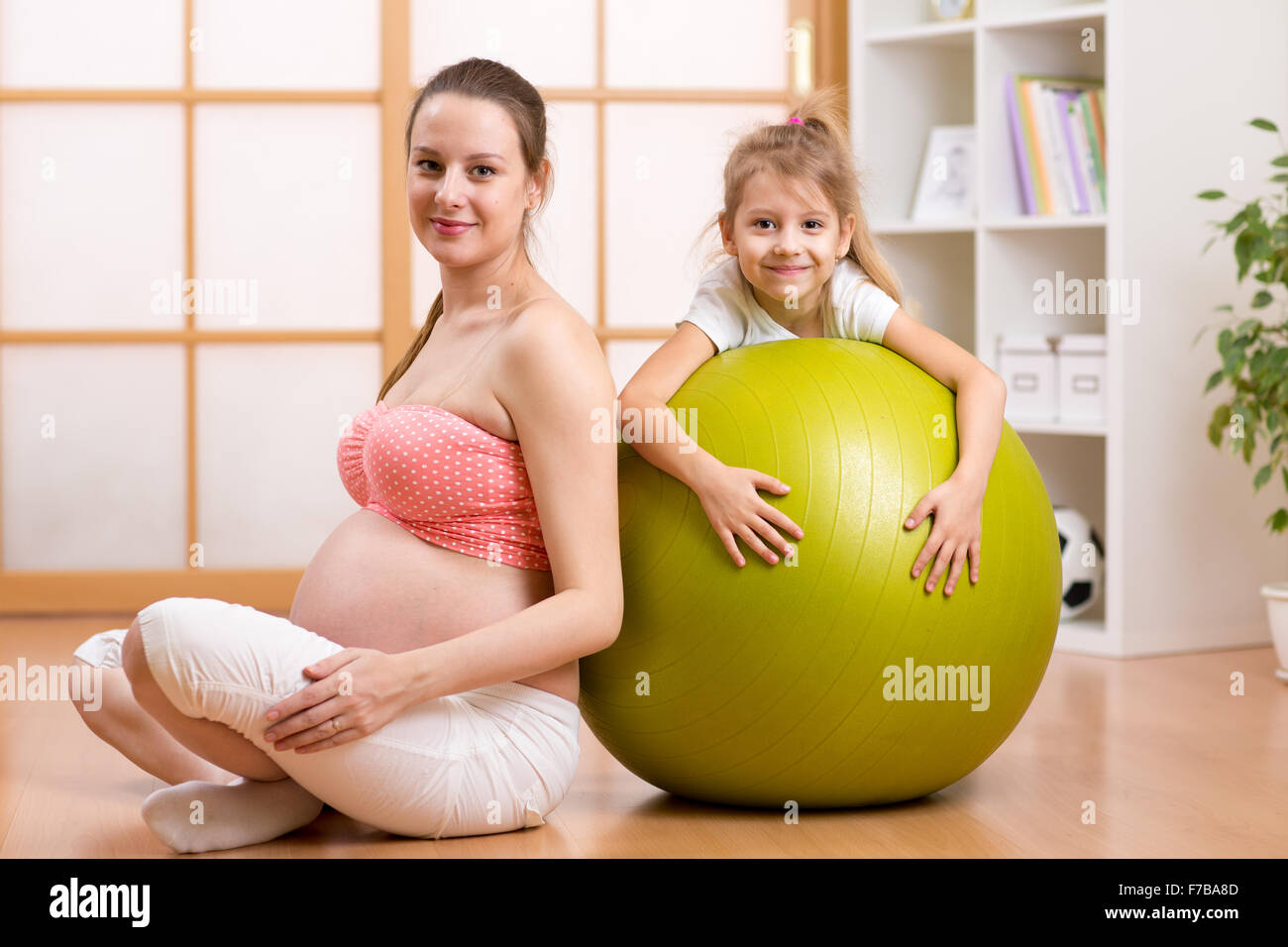 Familie, Kinder, Schwangerschaft, Fitness. Gesunder Lifestyle-Konzept - glücklich schwangere Frau mit Fitball zu Hause trainieren. Stockfoto