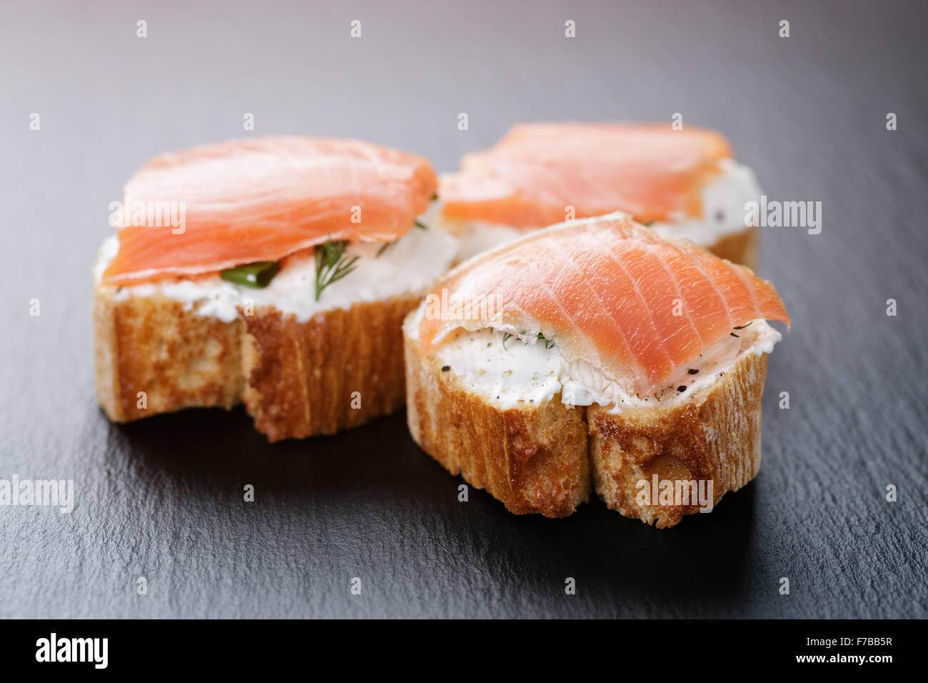 Baguette Scheiben mit Frischkäse und Lachs auf Schiefer Stockfotografie ...