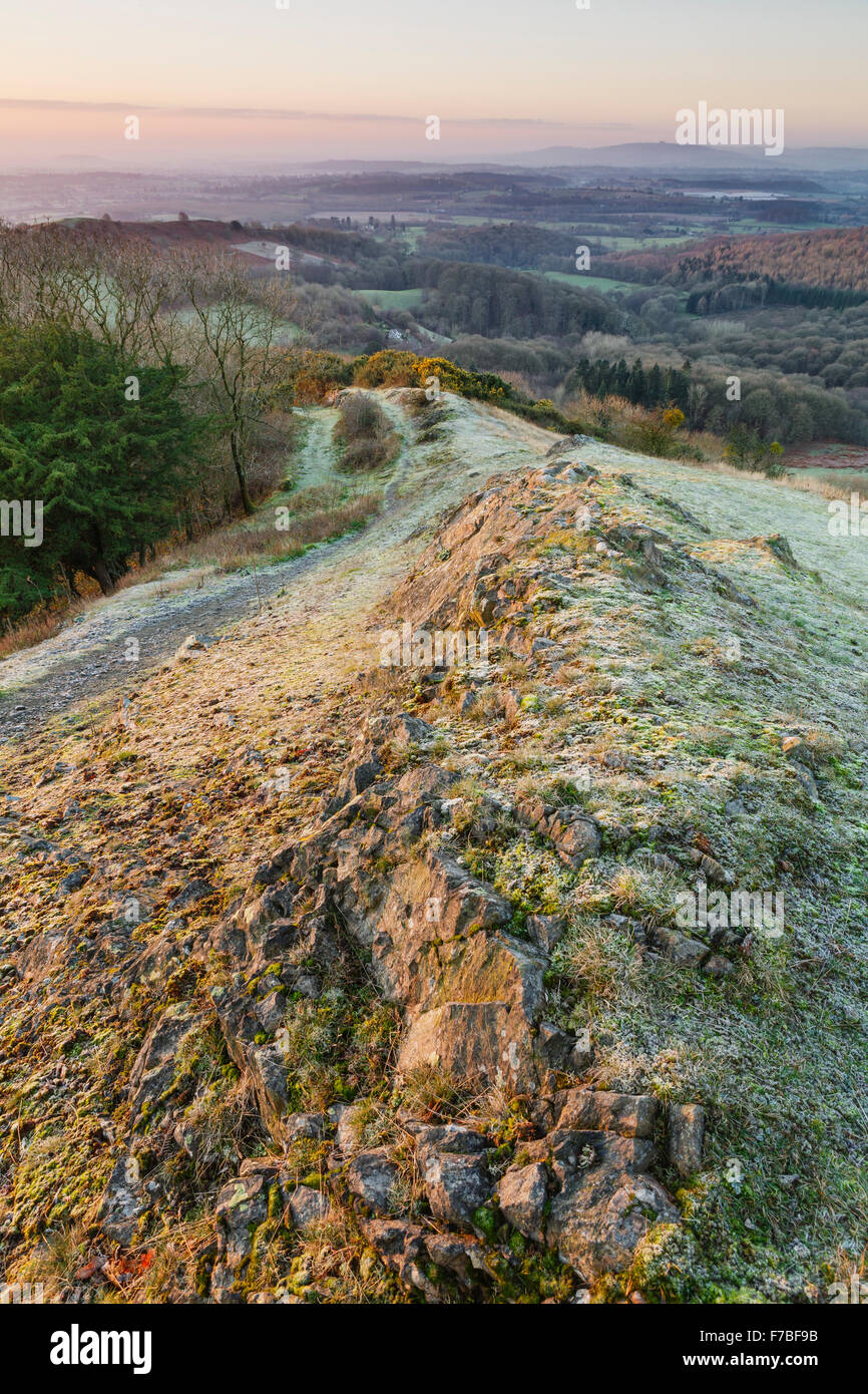 Sunrise leuchtet auf den Fußweg und Felsen über Raggedstone Hügel auf die Malvern Hills, Herefordshire an einem kalten frostigen Morgen. Stockfoto