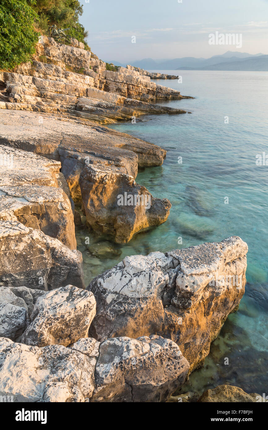 Felsen ragen aus dem Ionischen Meer in der Straße von Korfu in der Nähe von Kassiopi, Corfu, beim Sonnenaufgang über Albanien. Stockfoto