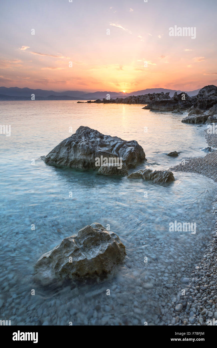 Die Sonne steigt über die Berge von Albanien über das Ionische Meer in der Straße von Korfu in der Nähe von Kassiopi, Corfu. Stockfoto