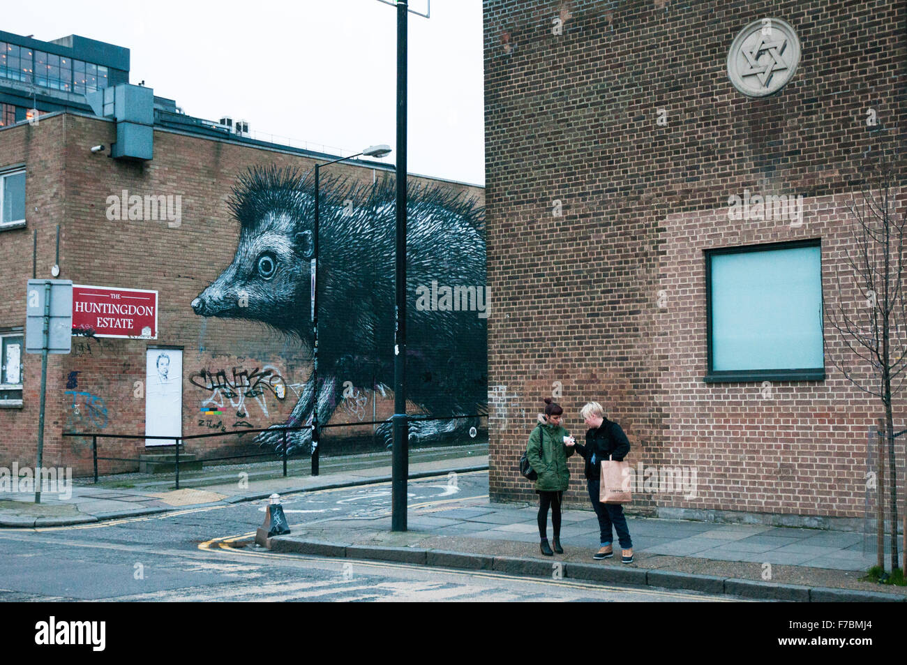 London, UK, 12 /2012.Two Frauen auf der Straße in der Nähe eine große Ratte Wandmalerei im Londoner East End. Stockfoto
