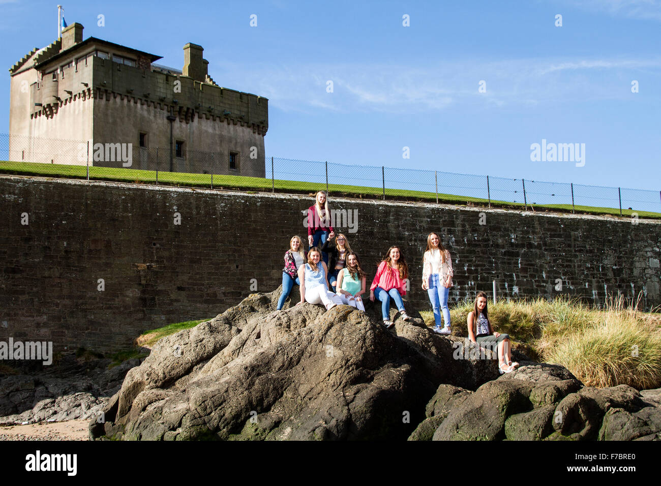 Eine Gruppe junger Mädchen, die einen lustigen Tag auf den Felsen am Strand vor dem Broughty Ferry Castle in Dundee, Großbritannien, genießen Stockfoto