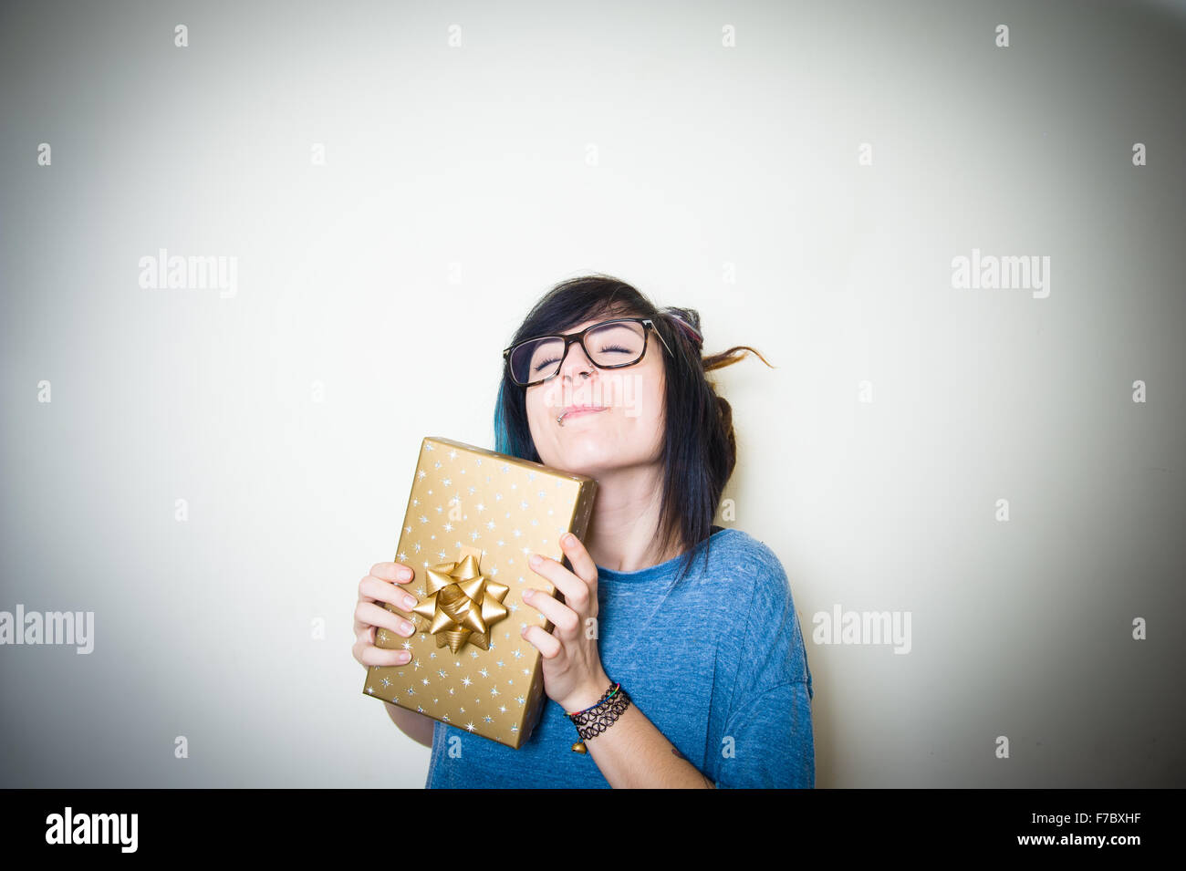Hübsche junge Teen Frau fröhlich gold Geschenkpaket zwischen den Händen zu halten Stockfoto