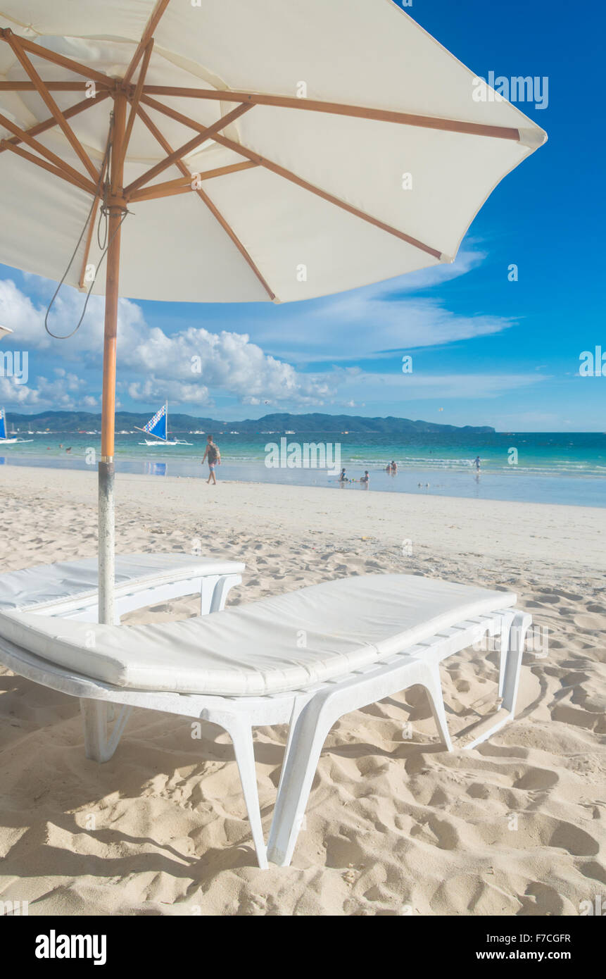 tropischer Strand mit weißem Schirm und Sessel Stockfoto
