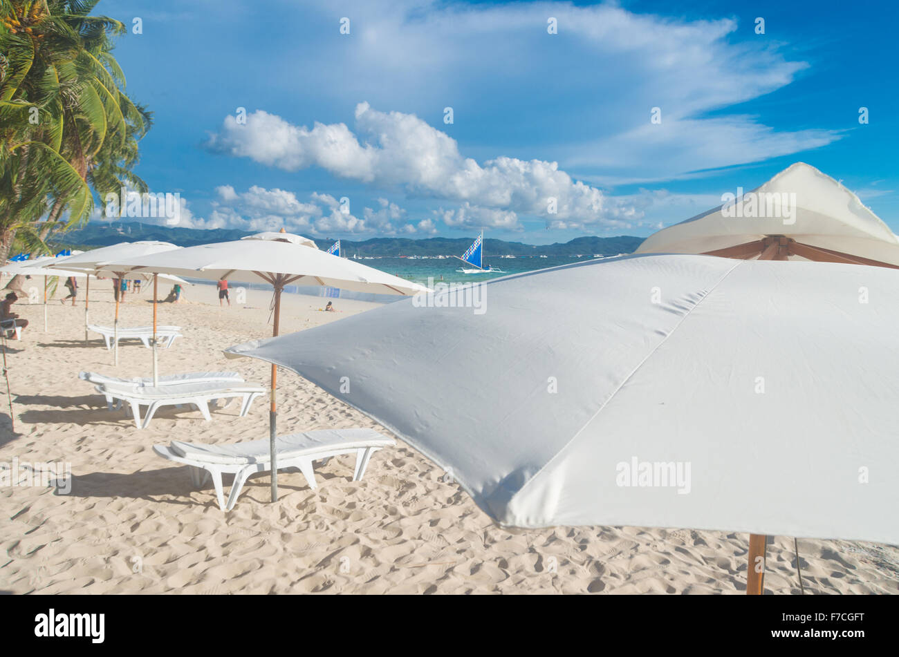 tropischer Strand mit weißen Sonnenschirmen und Liegestühlen Stockfoto