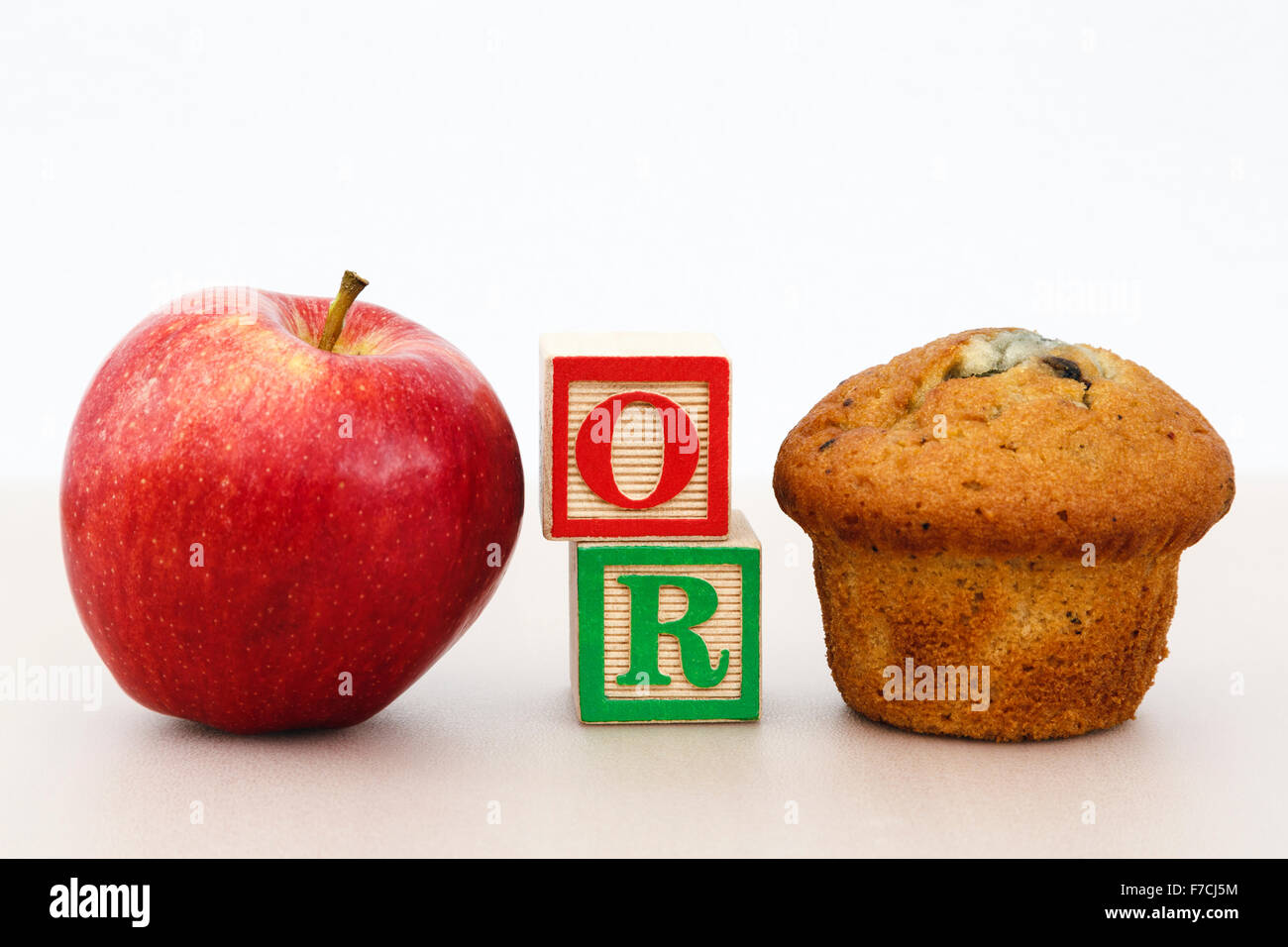 Rosy Red Apple und einen Muffin Kuchen mit Word oder im Schreiben Blöcke auf einer Tischplatte Wahl der gesund oder ungesund essen Konzept veranschaulicht gut Essen. Stockfoto