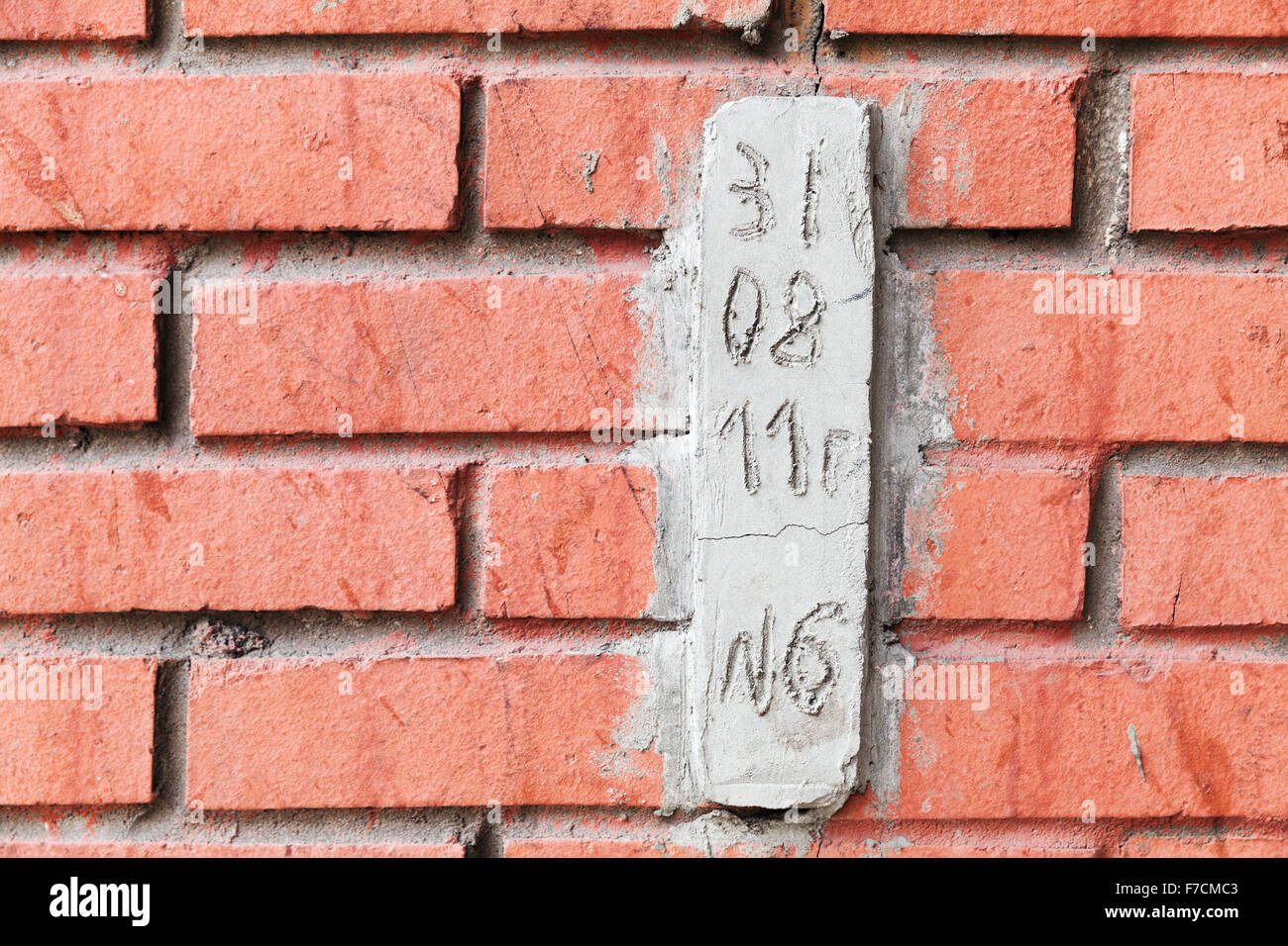 Spezielle Betonblock mit Datum zur Beobachtung von Rissen im roten Backsteinmauer Stockfoto