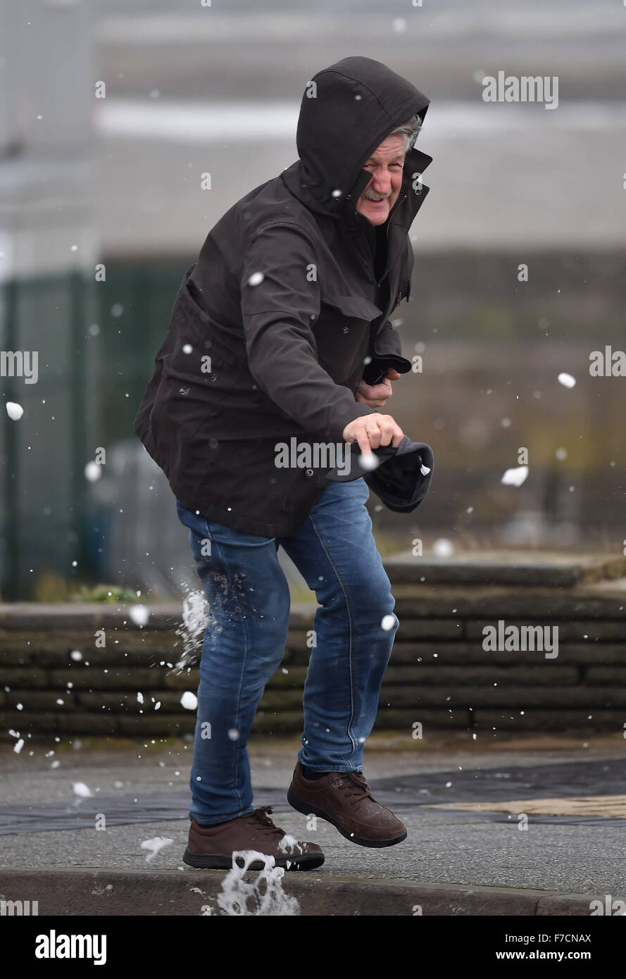 Ein Mann verliert fast seinen Hut bei starkem Wind verursacht durch Sturm Clodagh in Porthcawl Seafront, South Wales, UK. Stockfoto