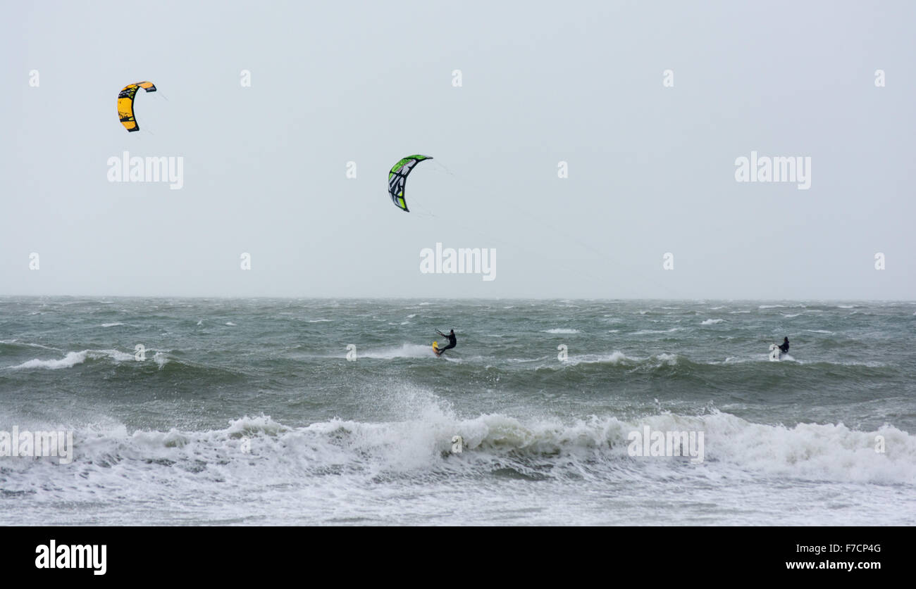 Kiter und Surfer reiten weiß schäumende Wellen in stürmischen Winter Wetter in Boscombe, Bournemouth, Dorset, Großbritannien Stockfoto