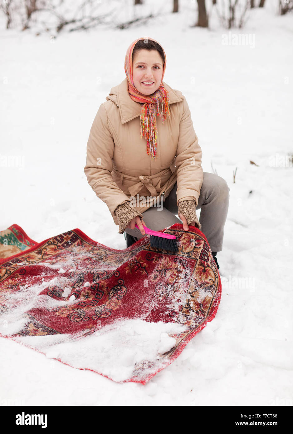 Russische Frau reinigt Teppich mit Schnee im Wintertag im freien Stockfoto