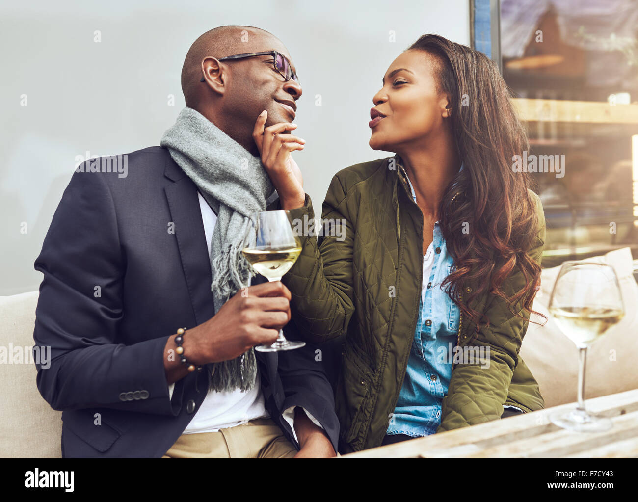 Junge attraktive afroamerikanische Frau flirten mit ihrem Freund Fältelungen ihre Lippen für einen Kuss und streichelte ihn am Kinn Stockfoto