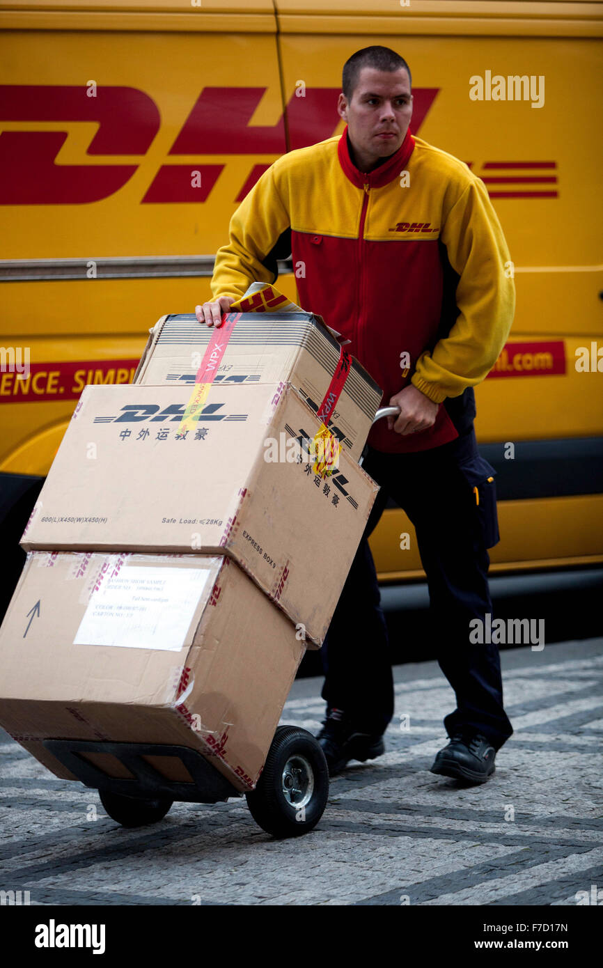 DHL-Mitarbeiter liefert Pakete, DHL-Paketzusteller schiebt den Wagen Stockfoto