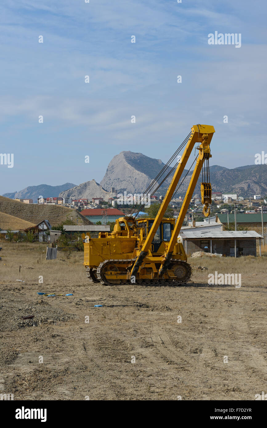 Gelbe Rohr Schicht Dozer ist bei Pipeline Gebäude Ort auf Hintergrund von Sudak, Schlossberg und Sokol (Hawk) Berg im Osten Stockfoto