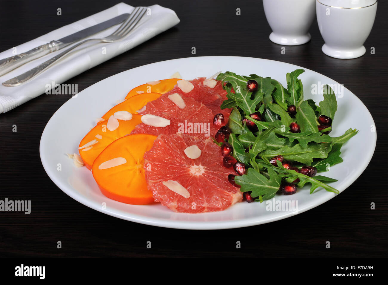 Salat mit Grapefruit, Kaki, Rucola, Mandeln und Granatapfel Stockfoto