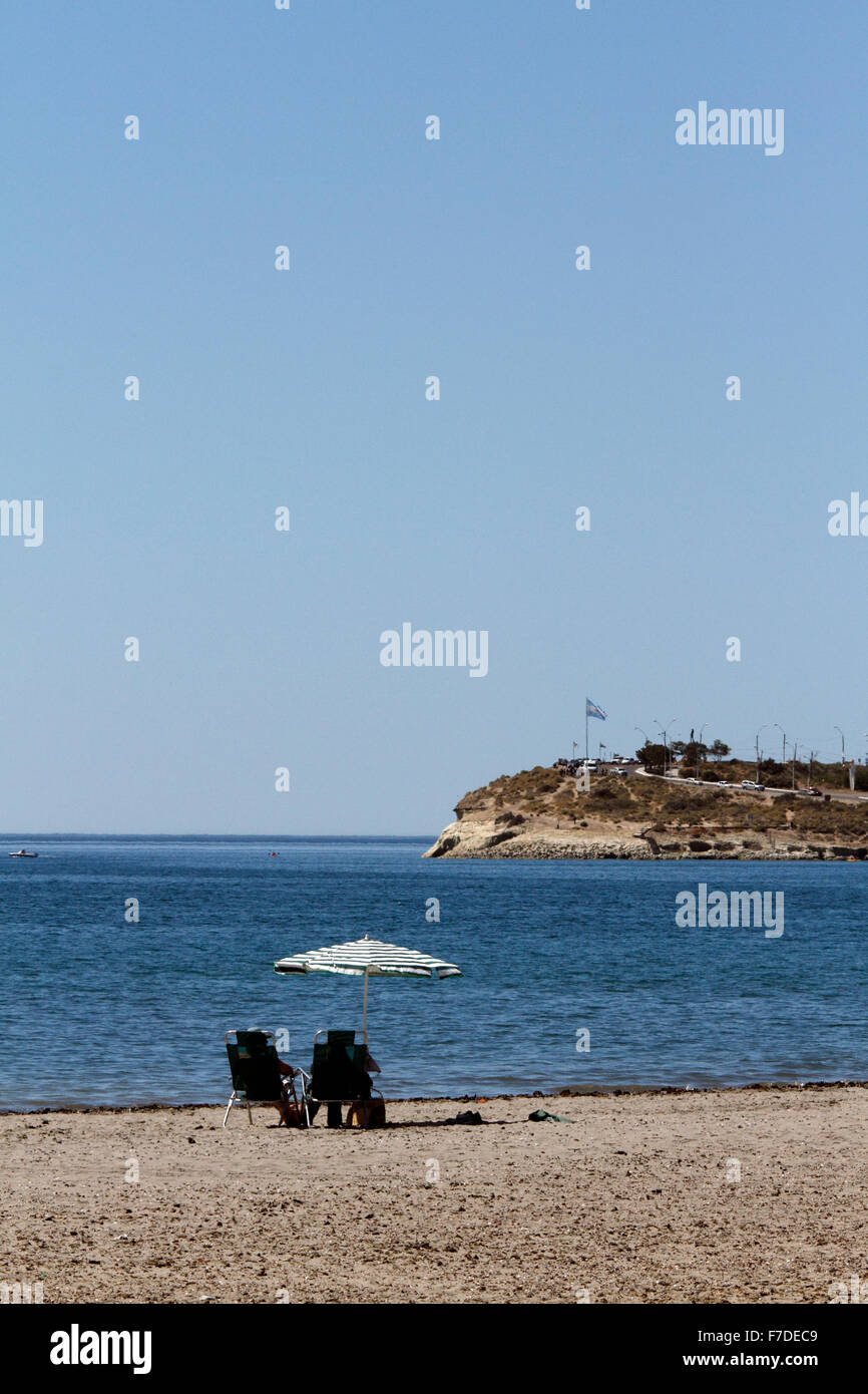 Der Strand von Puerto Madryn mit zwei Personen in einem leeren Strand mit Blick auf die Landzunge, wo die walisische Siedler gelandet. Stockfoto