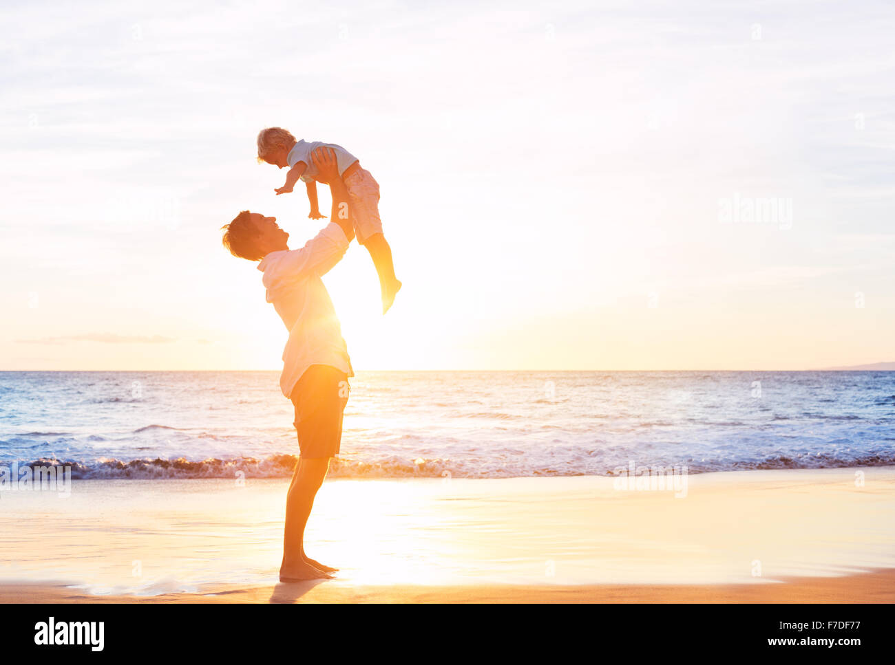 Glückliche freudige Vater und Sohn Spaß spielen am Strand bei Sonnenuntergang. Vaterschaft Familienkonzept Stockfoto