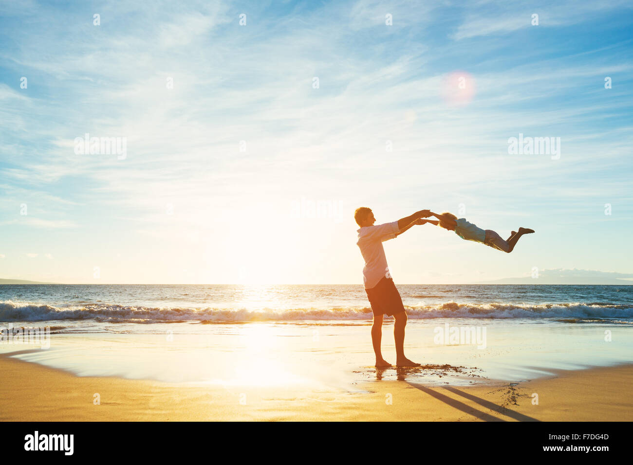 Glücklich fröhliche Vater und Sohn spielen am Strand bei Sonnenuntergang. Vaterschaft Familienkonzept Stockfoto