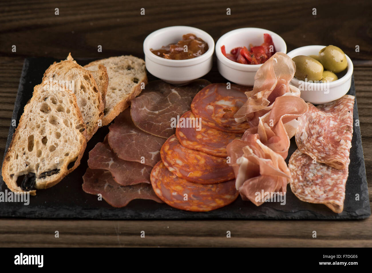 Italienische Wurst mit Chili, Chutney und Oliven als Vorspeise in einem italienischen Restaurant serviert. Stockfoto