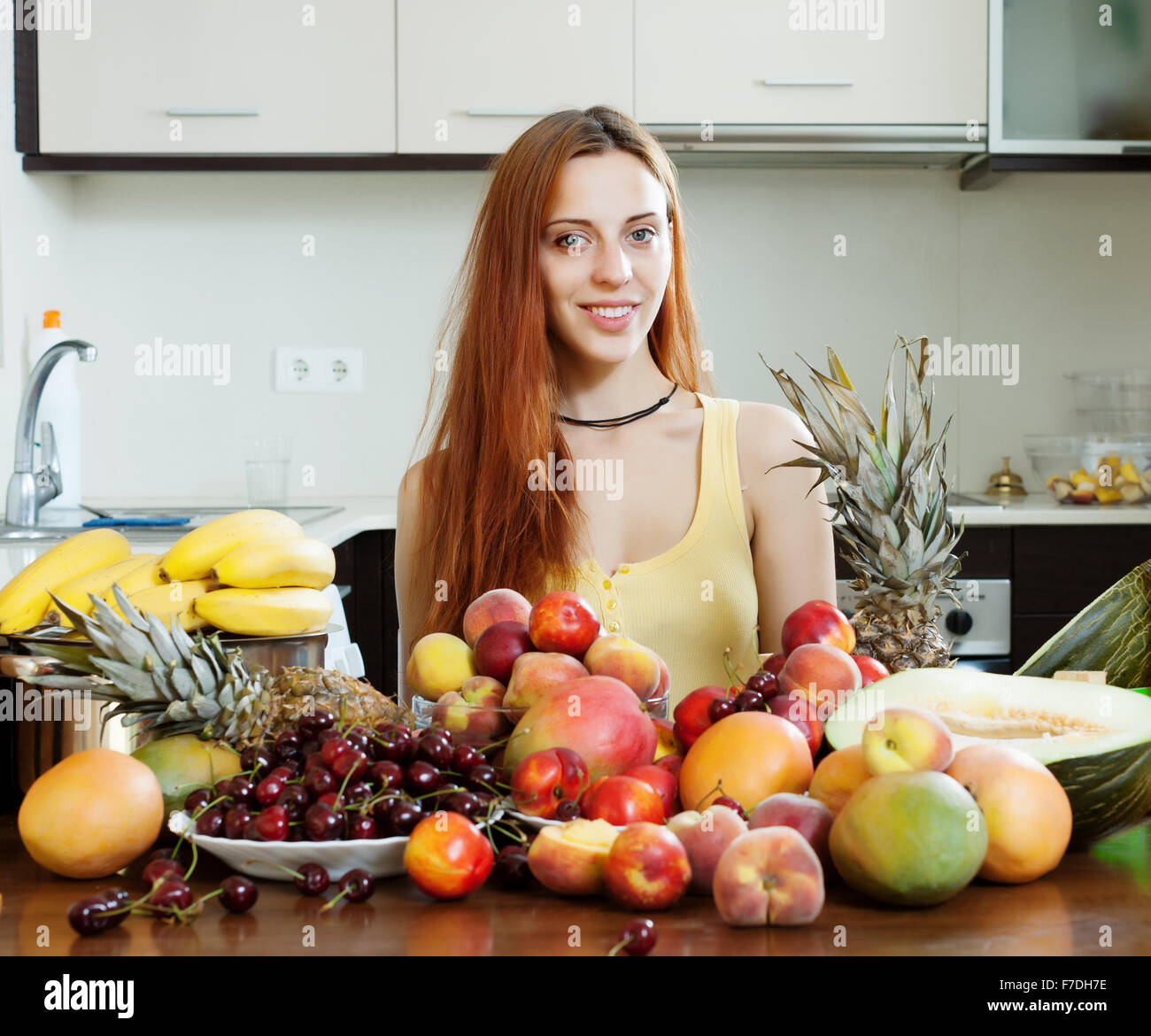 Positive Mädchen mit Haufen von Obst zu Hause Stockfoto