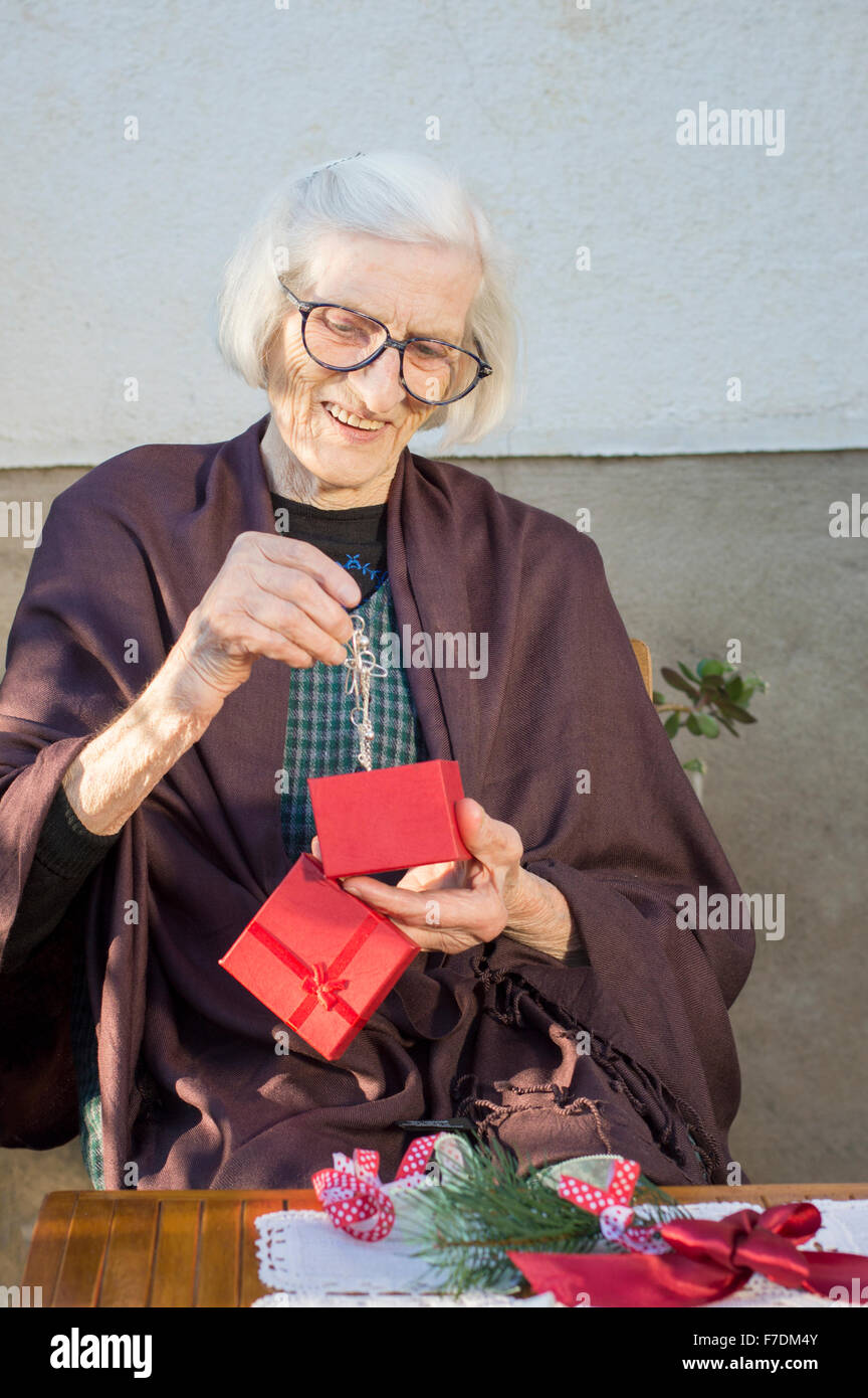 Ältere Frau betrachten ihr Weihnachtsgeschenk im Hinterhof Stockfoto