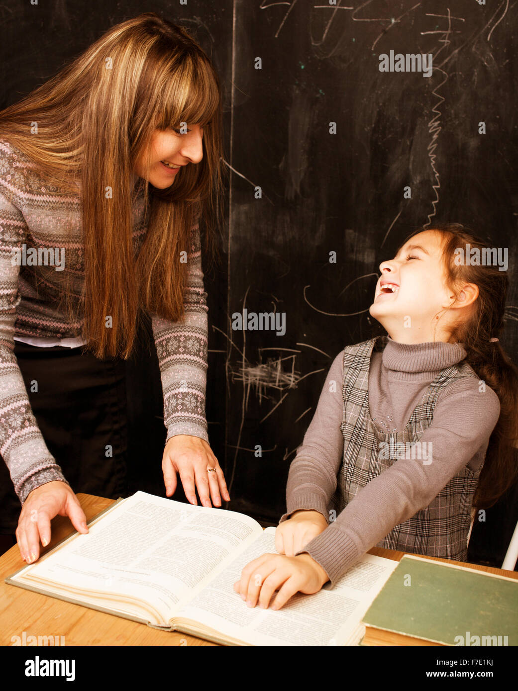 Lehrer mit Schüler im Klassenzimmer an der Tafel schreiben, Mädchen in der Schule Stockfoto