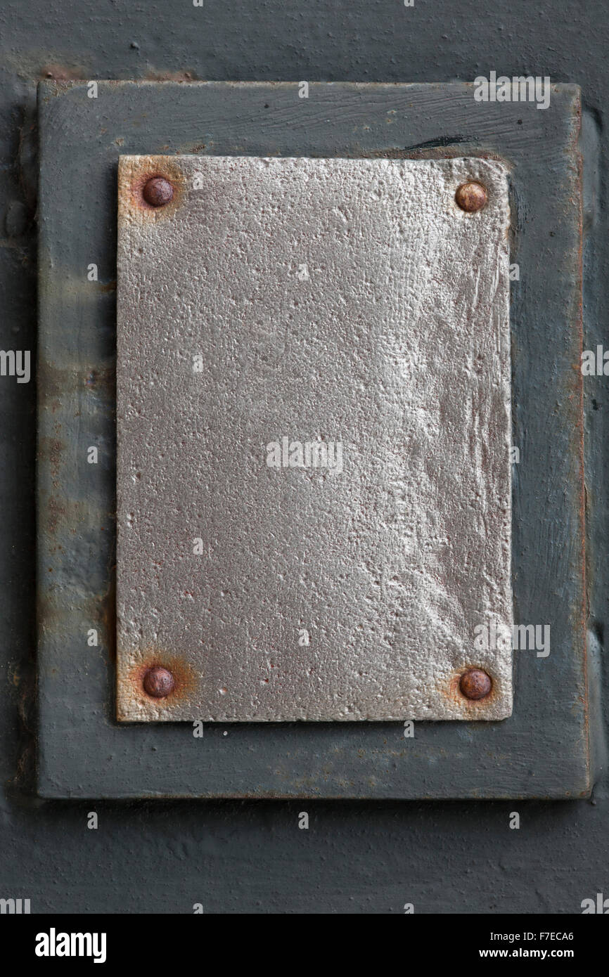 silberne Metallplatte mit Nieten auf grauem Hintergrund Stockfoto