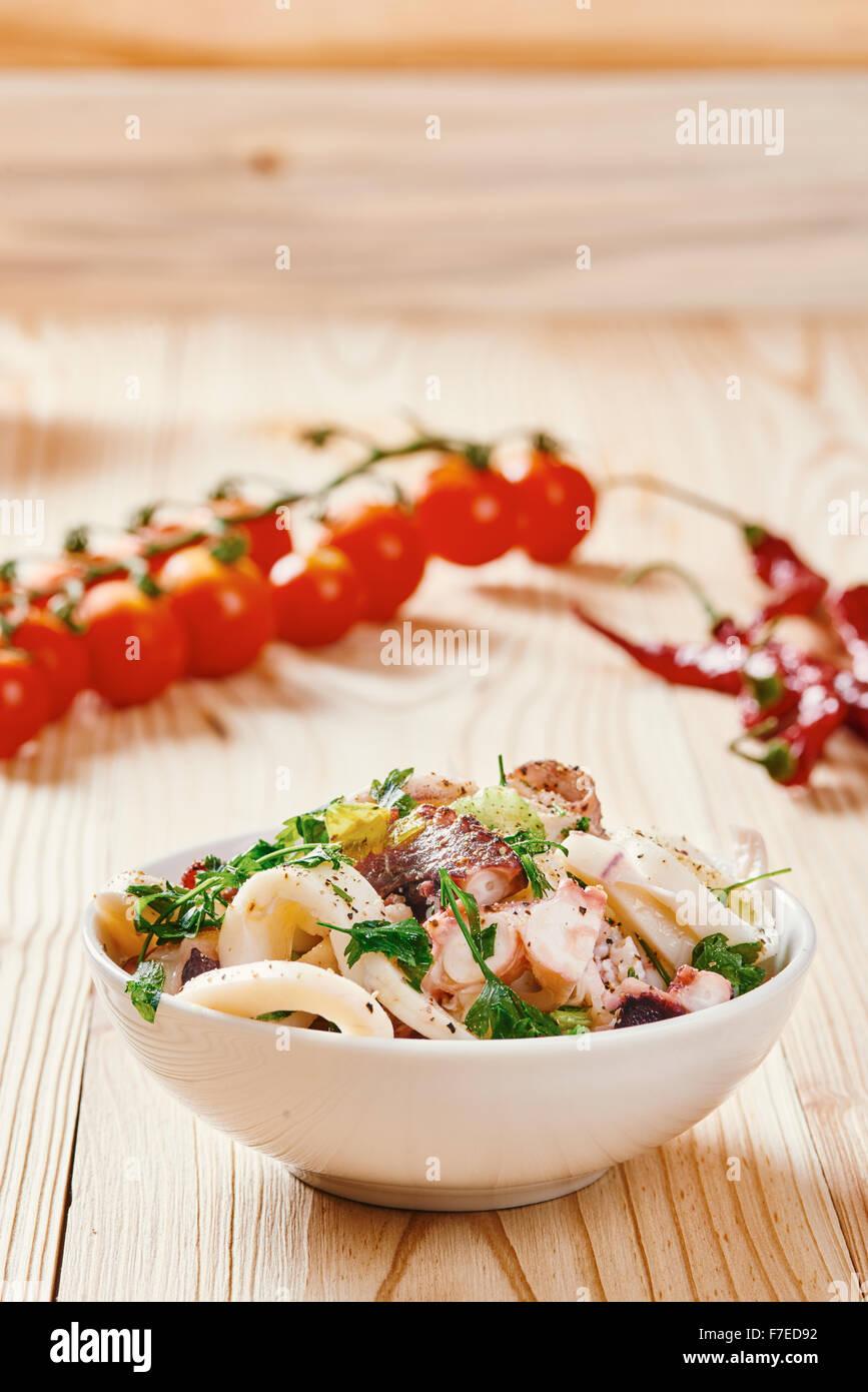 Meeresfrüchte-Salat in Schüssel weiß, Tomate, auf hellen Holztisch Stockfoto