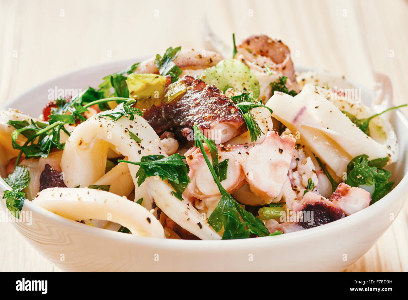 Meeresfrüchte-Salat in Schüssel weiß, Tomate, auf hellen Holztisch Stockfoto
