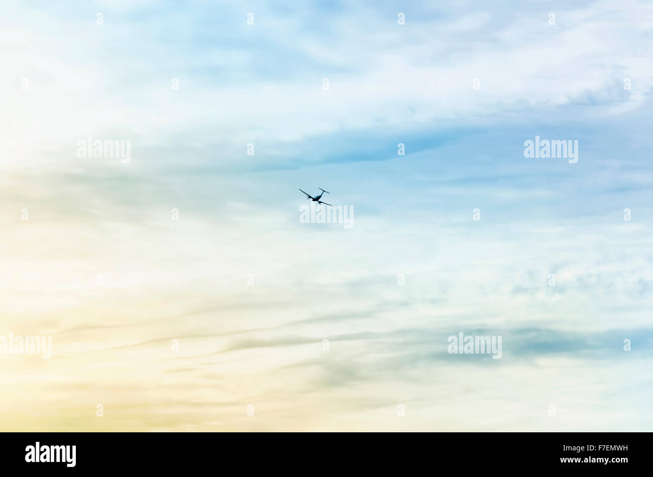 Silhouette der kleinen Flugzeug am Horizont. Es fliegt, wenn die Dämmerung zu brechen, an einem bewölkten Tag. Schönen Kontrast. Stockfoto