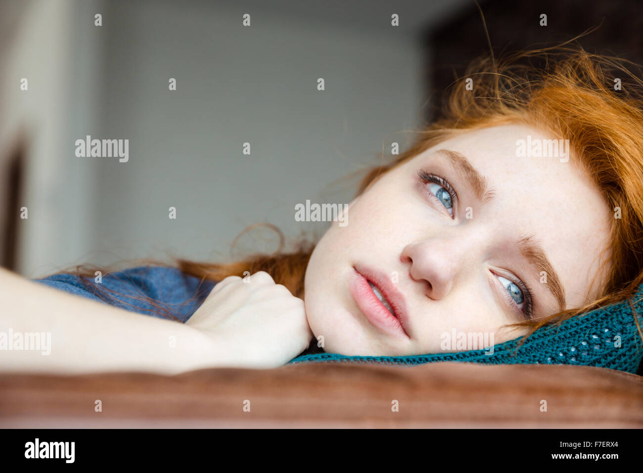 Nachdenklich verärgert müde junge Frau mit roten Haaren auf gestrickte Kissen liegend Stockfoto