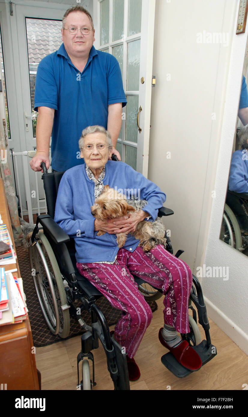 Männliche Pflegekraft schieben eine ältere Frau in einem Rollstuhl (Mutter & Sohn sein könnte) Stockfoto