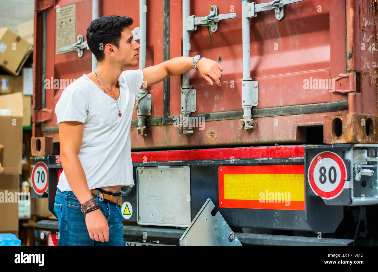 Taille bis Porträt des jungen lächelnd Mann neben LKW - entladen von Fracht aus Container Stockfoto