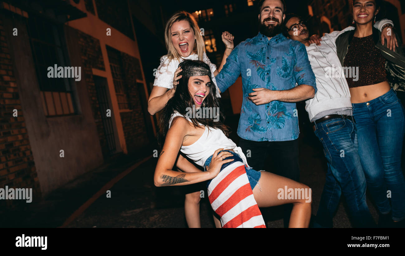 Porträt von ekstatischen junge Frau posiert auf Kamera während hängen mit ihren Freunden in der Nacht. Gruppe von Jugendlichen Gemischtrassig Stockfoto