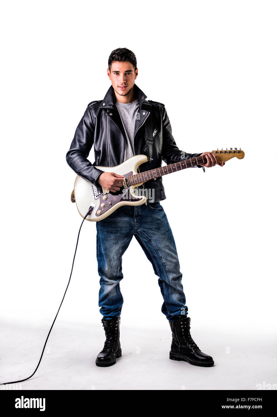 Full Length Portrait von junge Mann mit Lederjacke und Kampf Stiefel im Studio mit weißen Zeitmessung spielt e-Gitarre Stockfoto