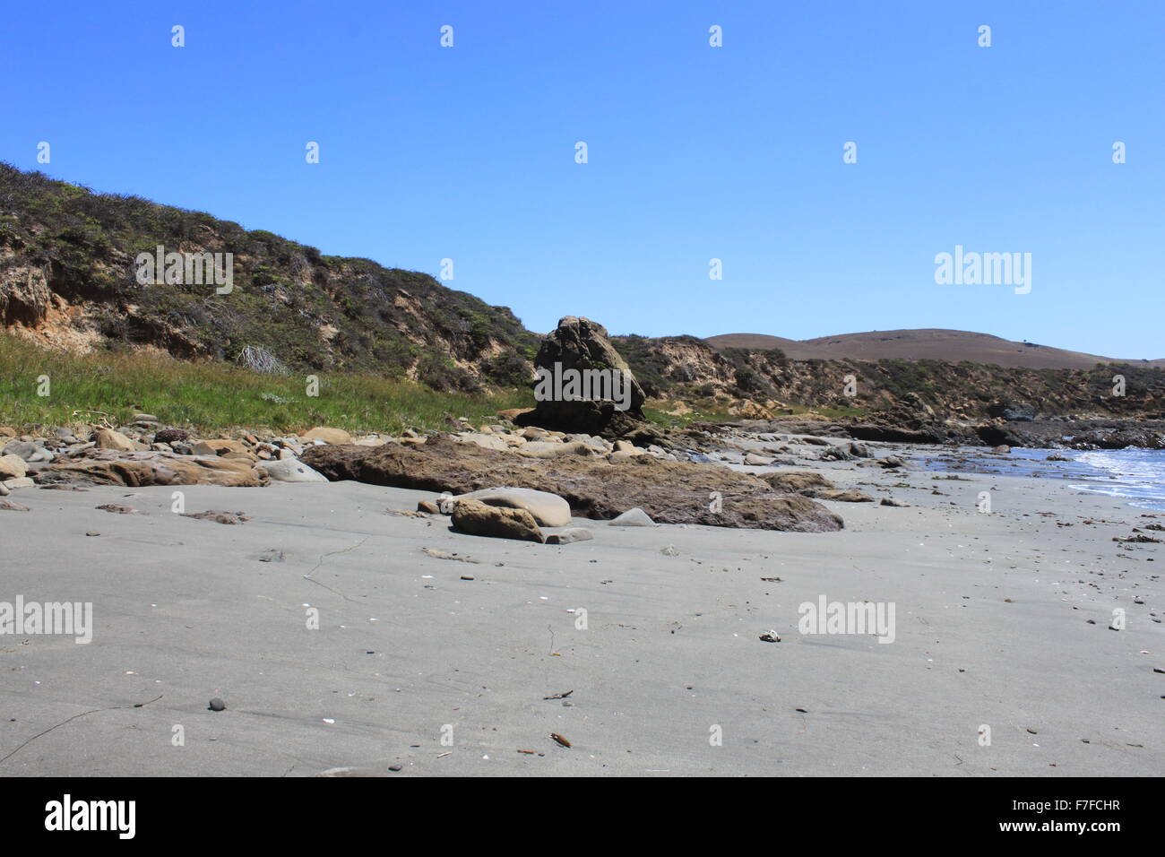 Felsen sitzen in den Sand Rasen und Pflanzen entlang des Strandes. Stockfoto