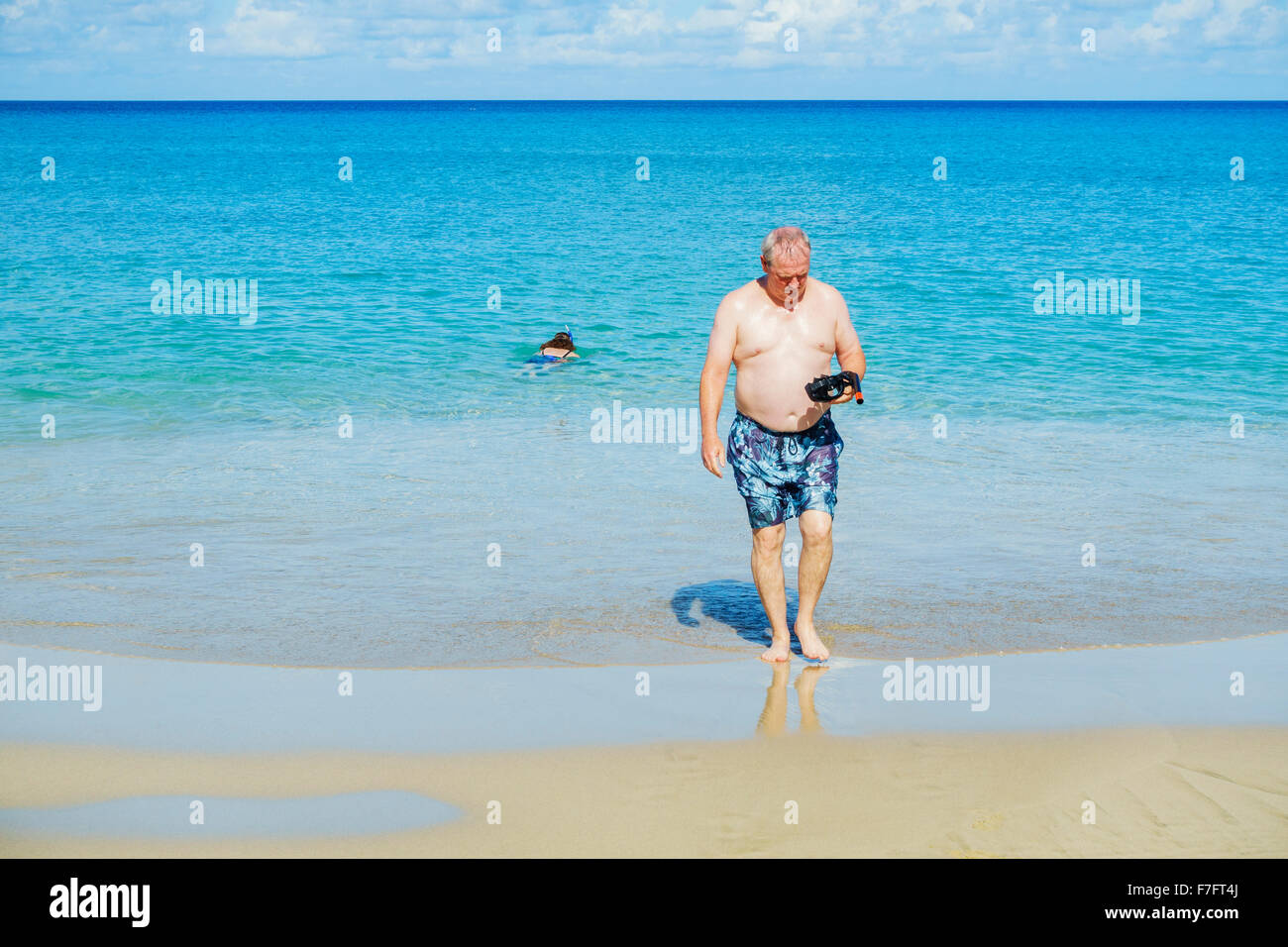 Ein 50 Jahre alter Mann inspiziert seine Maske und Schnorchel, wie er aus der Karibik zum Strand auf St. Croix, Amerikanische Jungferninseln kommt. USVI, U.S.V.I. Stockfoto