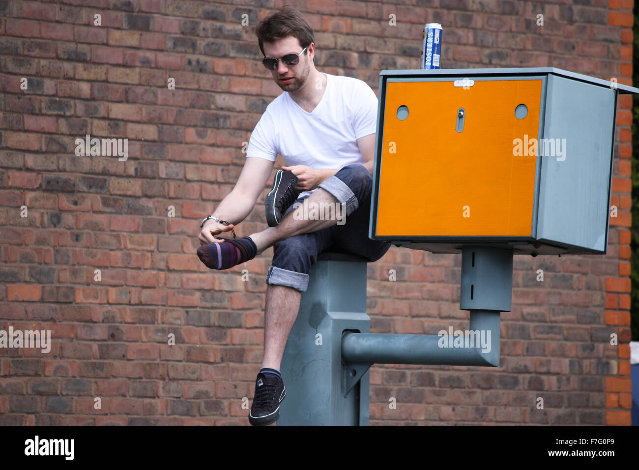 Junger Mann sitzt auf Geschwindigkeit Kamera Masten in London Stockfoto