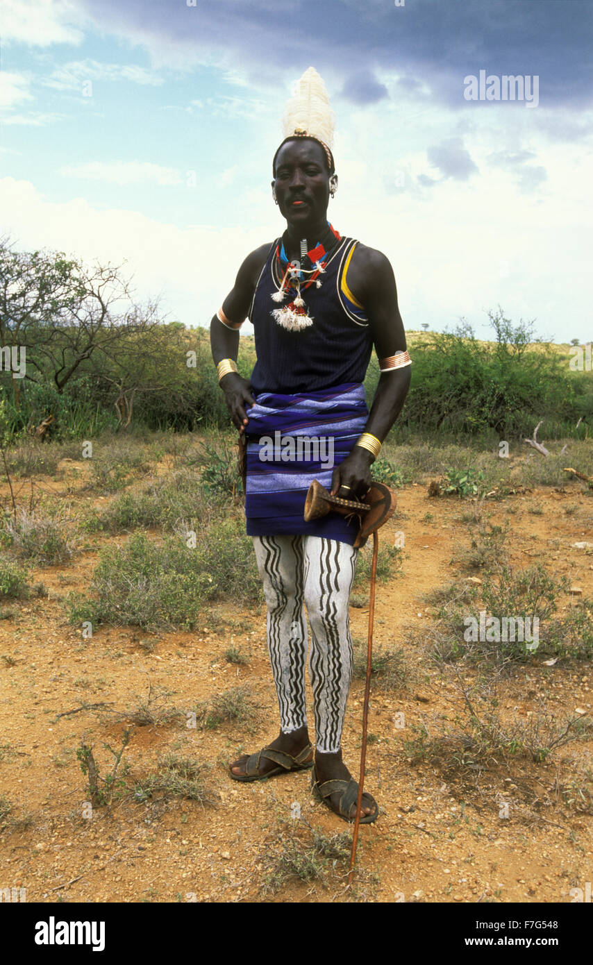 Hamar Mann mit lackierten Beinen, Straußenfeder Frisur und einem Hocker in der Hand posieren für ein Foto in Süd-Omo, Ehtiopia Stockfoto