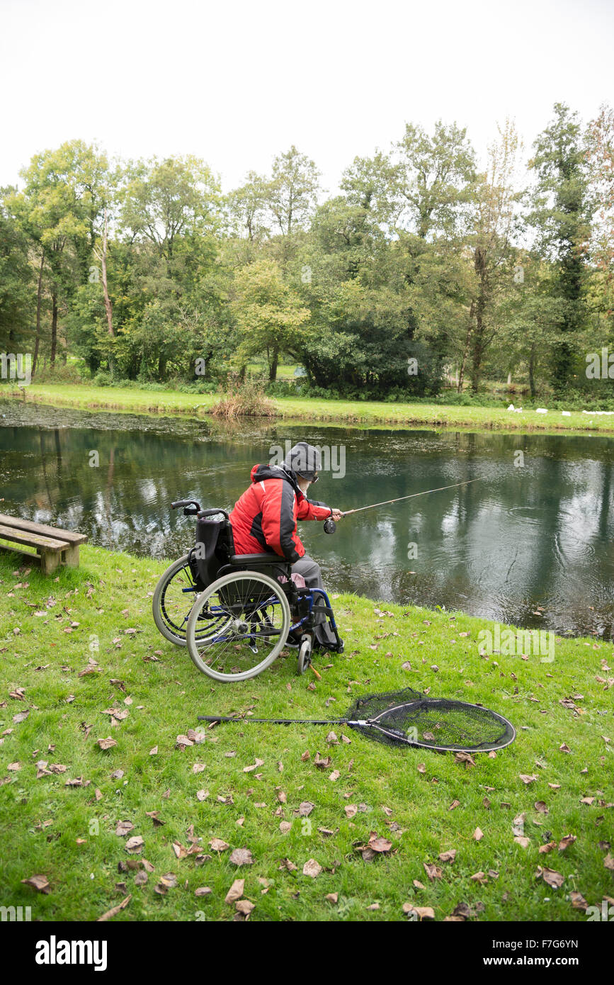 Ein behinderter Mensch fischt aus dem Rollstuhl Stockfoto