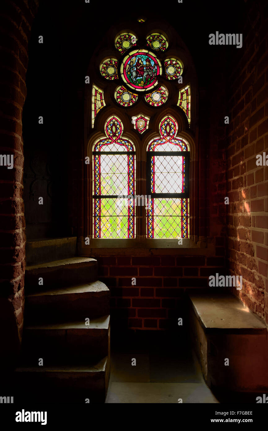Dunkle, geheimnisvolle Zimmer mit schönen Buntglasfenster in der mittelalterlichen Burg des Deutschen Ordens in Malbork, Polen. Stockfoto