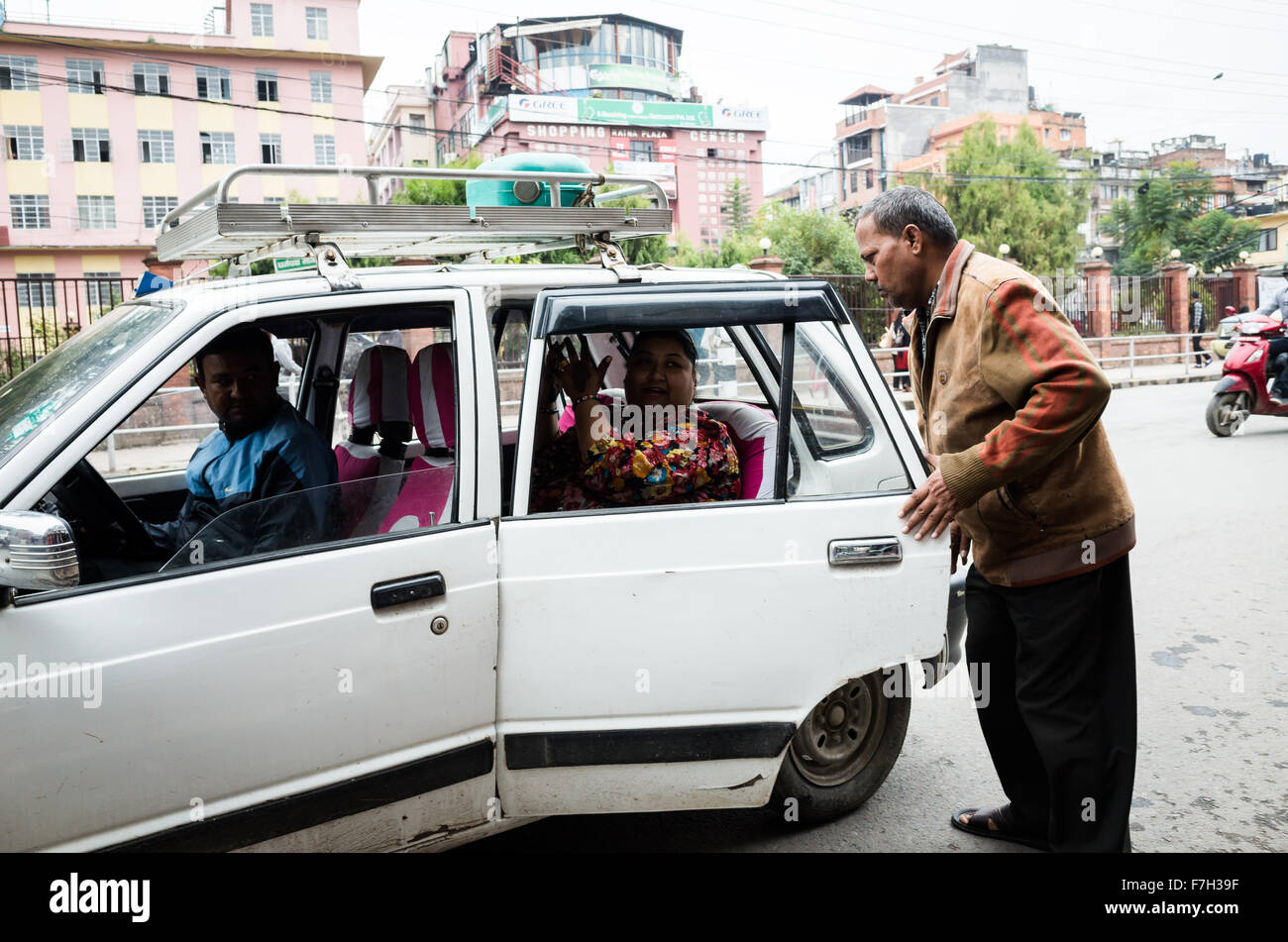 ein Mann mittleren Alters im Gespräch mit einer Frau mittleren Alters in ein Taxi auf der Straße der New Road, Kathmandu, 2015 Stockfoto